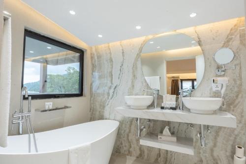 a bathroom with two sinks and a tub and a mirror at Coral Strand Smart Choice in Beau Vallon
