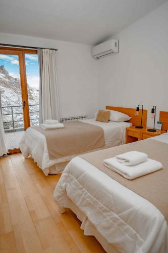 a hotel room with two beds and a window at Hostería Varvarco in Varvarco