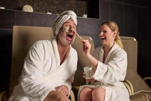 a woman sitting next to a man brushing his teeth at Hotel Bonvino Badacsony in Badacsonytomaj