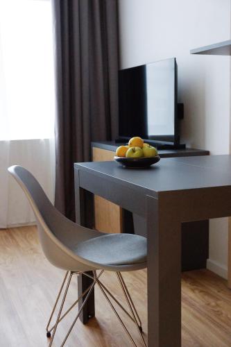 a table with a bowl of fruit and a chair at City Pop Prague Aparthotel in Prague