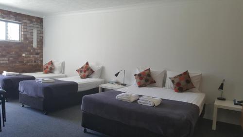 a room with three beds and a brick wall at Coomera Motor Inn in Gold Coast
