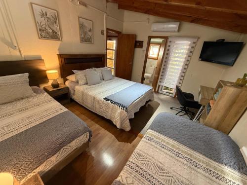a bedroom with two beds and a flat screen tv at Hostal Senderos del Sur in Freire