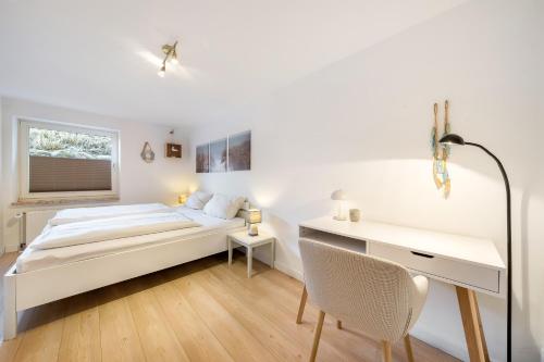 a white bedroom with a bed and a desk at Vierfuss 1A in Hörnum