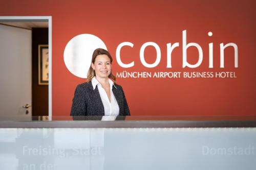 a woman standing at a podium in front of a sign at Corbin München Airport Business Hotel in Freising