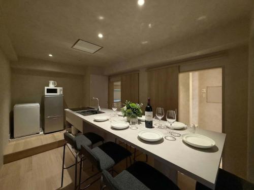 a kitchen with a table with plates and wine glasses at Ishiki by b hotel - Next to Station Newly Renovated 3BR with Island Kitchen in Hiroshima