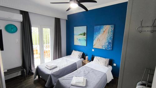 a room with two beds and a blue wall at House with a pool, 2' from the beach in Kineta