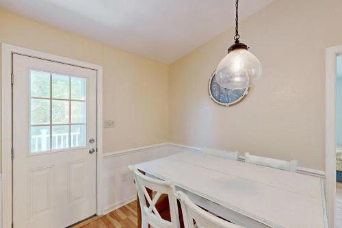 a dining room with a white table and a window at Worries not Found in Kill Devil Hills