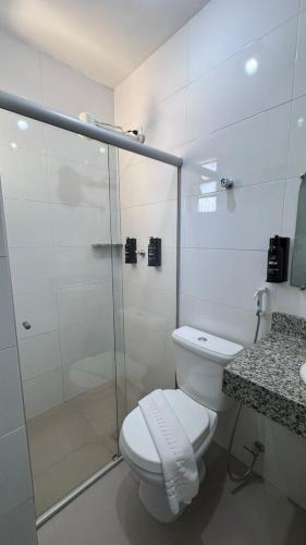 a bathroom with a toilet and a glass shower at Bittar Inn in Brasília