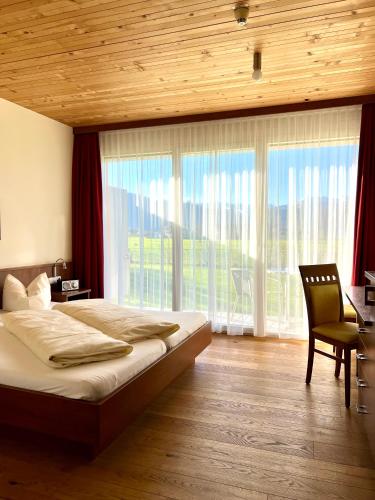 a bedroom with a bed and a desk and windows at Vitalhotel Quellengarten - Bed & Breakfast in Lingenau