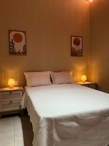 a bedroom with a white bed with two night stands at Casa Tito in Cascavel