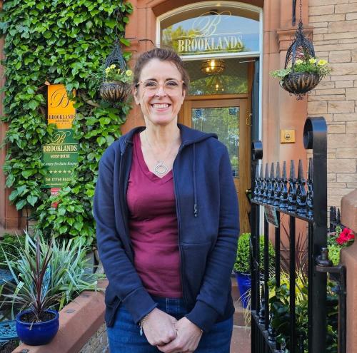 a woman standing in front of a building at Brooklands 5 Star Guest House in Penrith