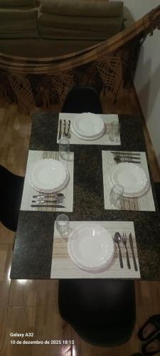 a table with white plates and silverware on it at Aconchego das Araras in Sirinhaém