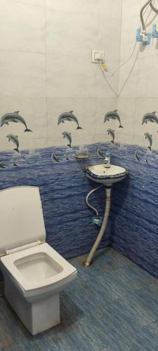 a bathroom with a toilet and a sink with birds on the wall at Chohan guest house in Khātu