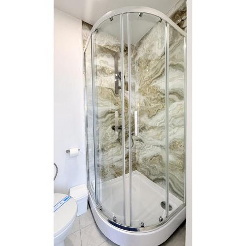 a shower in a bathroom with a stone wall at Kharkiv Prime Center Apartmens on Sumska 46 in Kharkiv