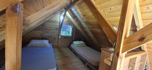 an attic room with two beds in a log cabin at Pousada PortoBello Praia do Rosa in Imbituba