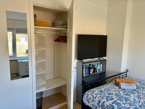a bedroom with a bed and a tv and shelves at Nijmegen Cozy Guest Rooms in Nijmegen