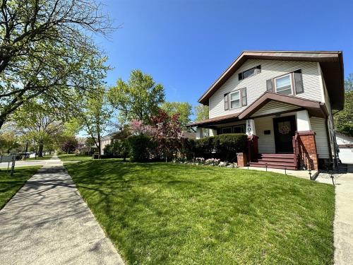 a house with a grass yard and a sidewalk at King Bed, Stocked Kitchen, Easy Driveway Parking, 2mi to Downtown & Coliseum in Fort Wayne