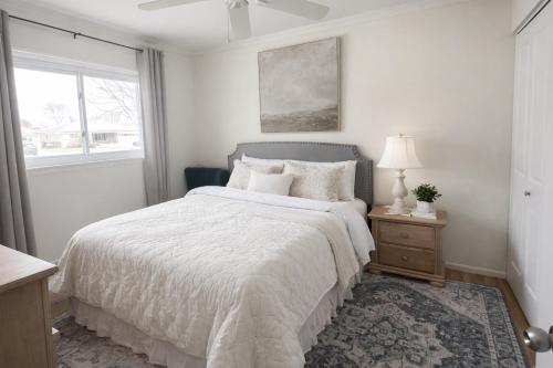 a white bedroom with a bed and a window at Charming Getaway Make Memories in Sterling Heights