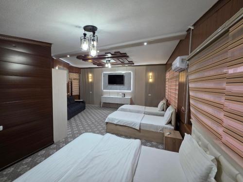 a hotel room with two beds and a television at Al Samarqandi Hotel in Samarkand