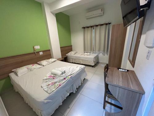 two beds in a room with green walls at Hotel Santa Clara in Aparecida