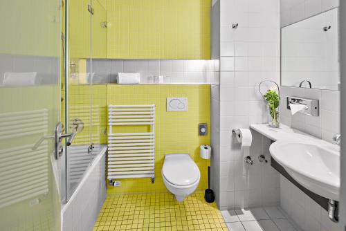 a yellow bathroom with a toilet and a sink at Hotel an der Stadtmauer in Schorndorf
