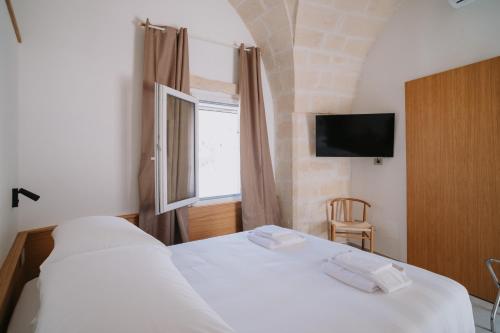 a bedroom with a white bed and a window at Cavae - Le stanze in Massafra