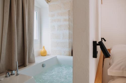 a bath tub in a bedroom with a window at Cavae - Le stanze in Massafra