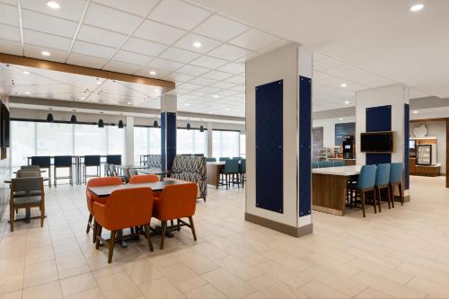 a cafeteria with a table and chairs and a bar at Holiday Inn Express & Suites Anchorage - Midtown in Anchorage