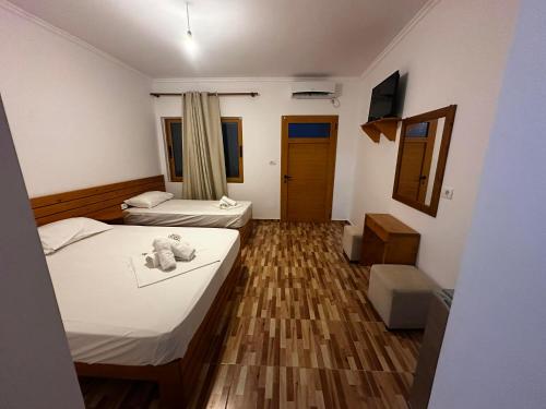 a bedroom with two beds and a teddy bear on the floor at Beleris Rooms in Himare