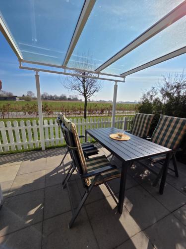 a table and chairs on a patio with a fence at Ferienhaus Seemöwe mit Deichblick Butjadingen-Burhave in Burhave