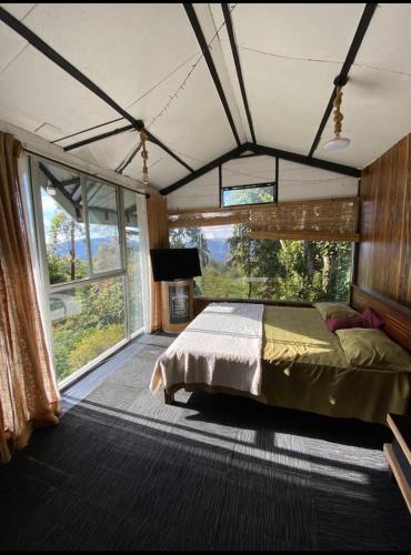 a bedroom with a bed and a large window at Kithul Cottage in Nuwara Eliya