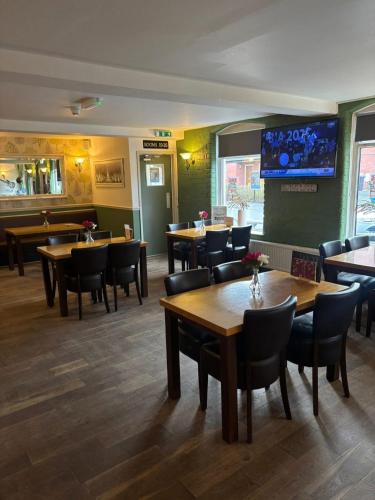 a restaurant with tables and chairs and a tv on the wall at Liberal House Tamworth in Tamworth