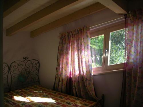 a bedroom with a bed and a window with curtains at Villa Susina Casa Vacanze in Toscolano Maderno