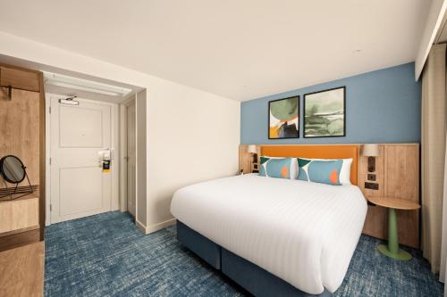 a hotel room with a large bed and a door at voco Letchworth Hall by IHG in Letchworth