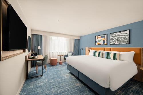 a hotel room with a large bed and a desk at voco Letchworth Hall by IHG in Letchworth