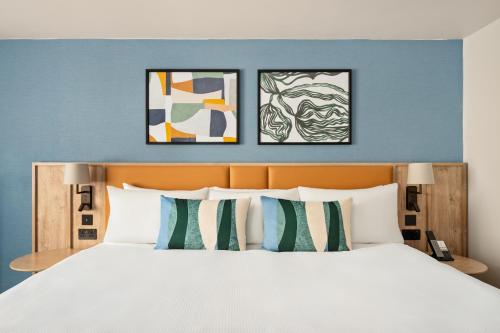 a bedroom with a bed with three paintings on the wall at voco Letchworth Hall by IHG in Letchworth