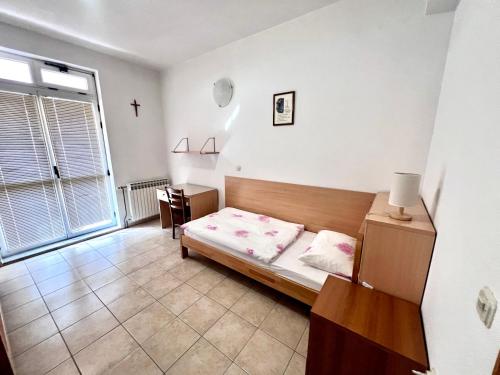 a bedroom with a bed and a table and a window at Paxora sobe - Mostar in Mostar