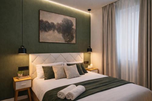 a bedroom with a large bed with two towels on it at Ohana Boutique Málaga Centro in Málaga