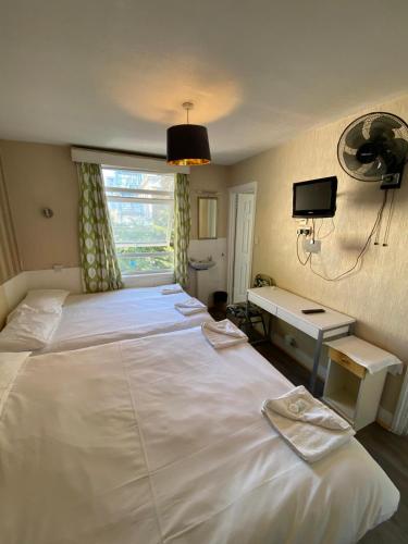 a large white bed in a bedroom with a window at Earl's Court Rooms in London