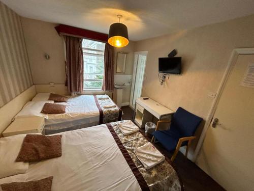 a hotel room with two beds and a chair at Earl's Court Rooms in London