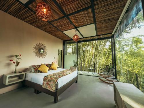 a bedroom with a bed and a large window at Hotel Terra Tacuara in Armenia