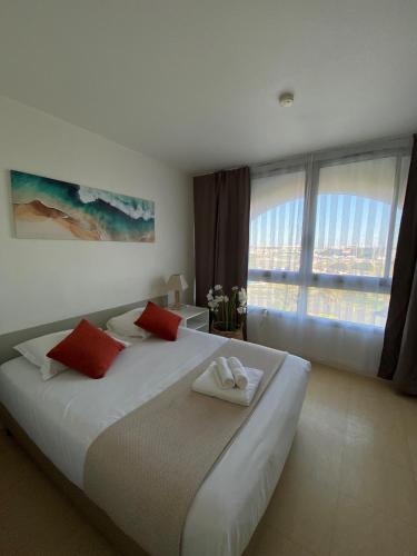 a bedroom with a large white bed with red pillows at Résidence avec Piscine face au port 200m plage in La Rochelle
