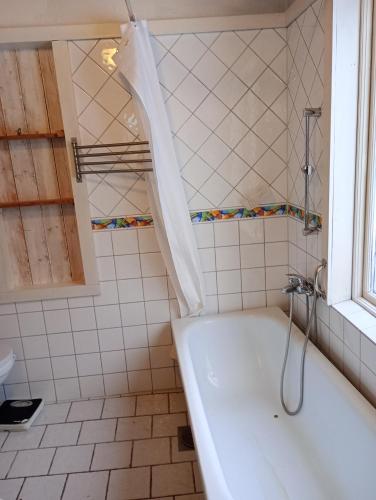 a white tub in a bathroom with a window at Herrgårdsvillan in Tjurkö