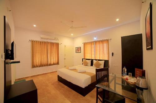 a hotel room with a bed and a glass table at Heritage Shelters Resort in Mysore