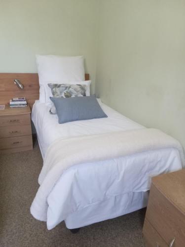 a bedroom with a white bed with a blue pillow at Ebenezer Verblyf in Fraserburg