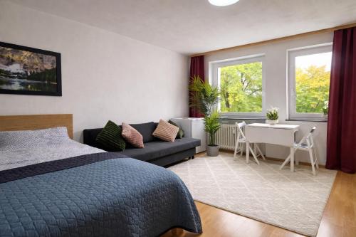 a bedroom with a bed and a couch and a table at Quiet & Modern Studio near Tram & River Lech in Augsburg