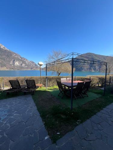 a picnic table and chairs with a view of the water at Cà Serena Panoramic Garden - Appartamento Greta in Ledro