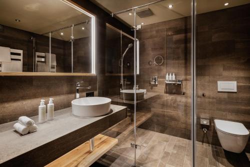 a bathroom with a shower and a sink and a toilet at Berghotel Kleiner Biber in Warth am Arlberg