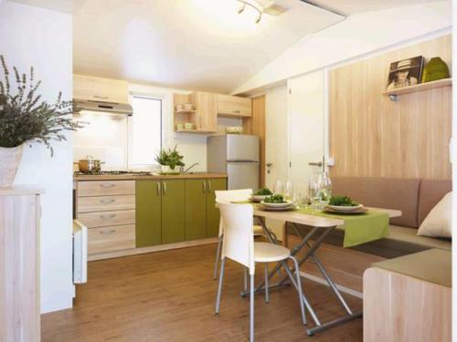 a kitchen with a table and chairs in a room at Mobile Homes Victoria San Marino in Lopar