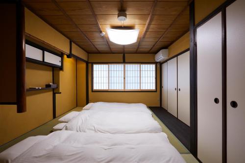 a room with a row of white beds in it at Miro Hachijo Uchidacho Tei in Kyoto